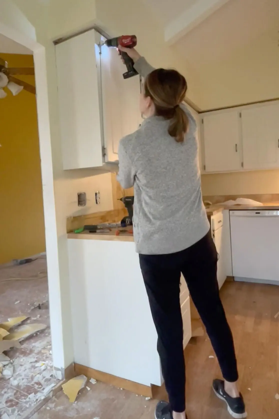 Woman removing old kitchen cabinets.